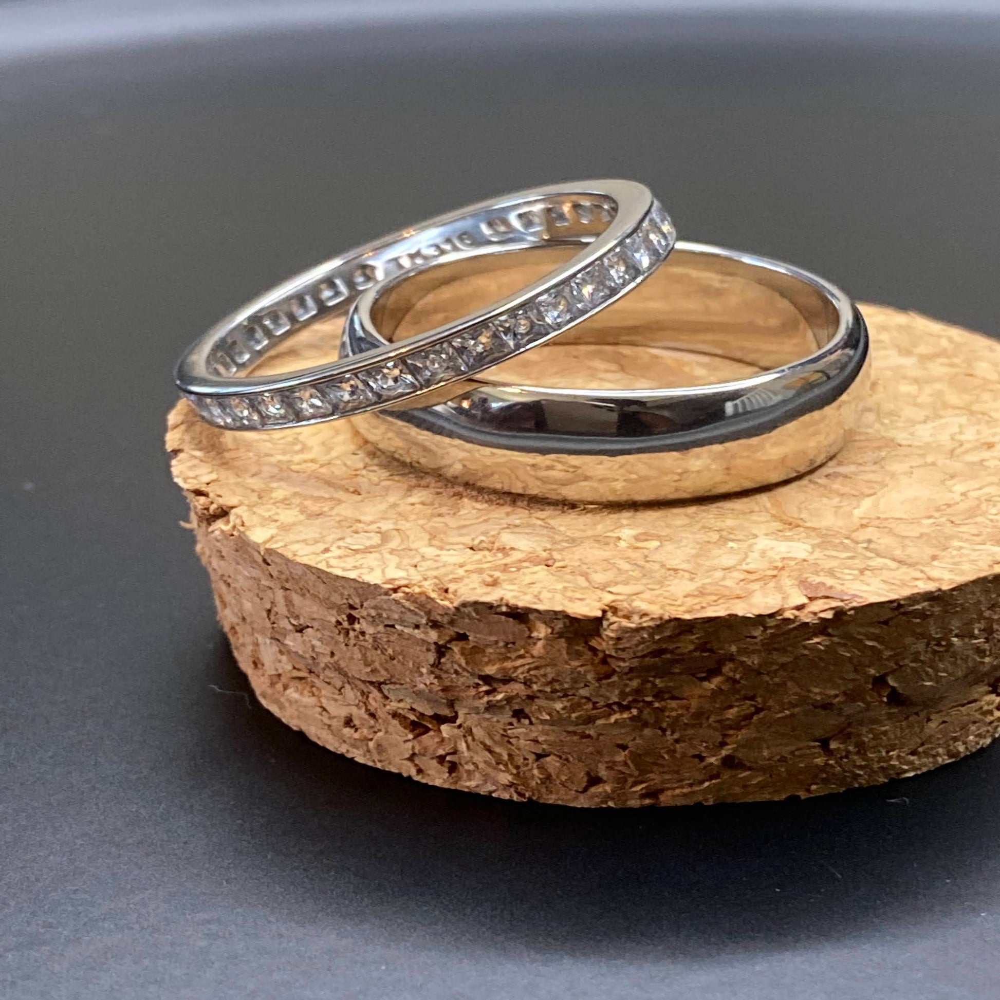 Silver 2 ring set includes a thick, solid band & a channel-set thin band with square zircon stones. Made from high-quality stainless steel, these rings are designed for plus-sized fingers.